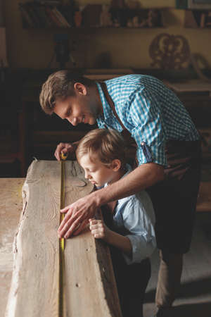 Smiling father and son measuring a boardの写真素材