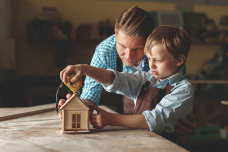 Father and son with a wooden house indoorsの写真素材