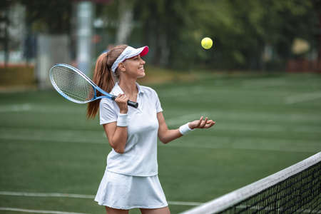 Young smiling girl playing tennis outdoorsの写真素材