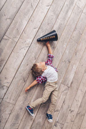 Little boy with a megaphone on the wooden floorの写真素材