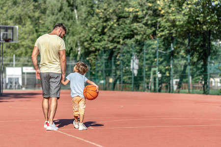 Father and son on the basketball court in summerの写真素材