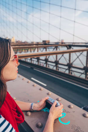 Attractive girl with a camera on Brooklyn Bridge in New Yorkの写真素材