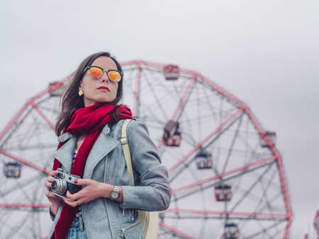 Young girl with retro camera on background of the ferris wheelの写真素材