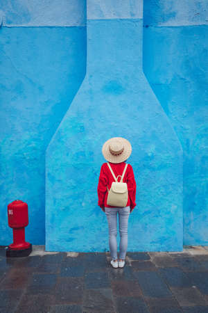 Young girl with a backpack on a background of blue wallの写真素材