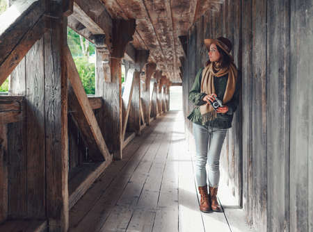 Attractive girl with a retro camera on a wooden bridge