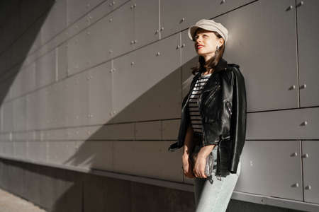 Attractive girl in stylish outfit at the wall