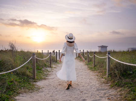 Young girl in a white dress on the beach in the morningの写真素材