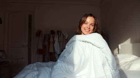 Smiling girl in bed in the morningの写真素材