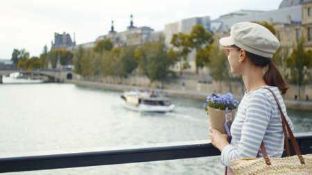 Beautiful girl with flowers on the bridge in Parisの写真素材