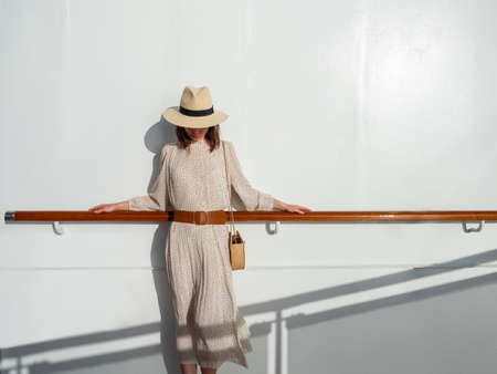 Young woman in a hat by the wall in the sunの写真素材