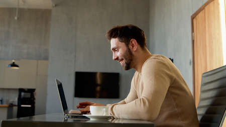 Man doing video chat for distance communication. Young male with laptop at the desk at homeの写真素材