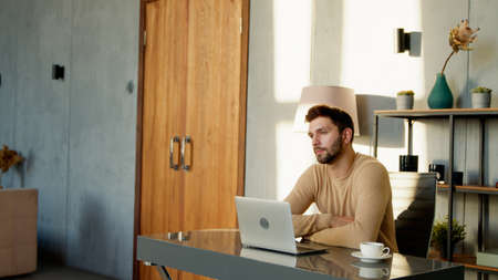 Young freelancer man working on computer at home. Handsome worker with laptop computer indoorの写真素材