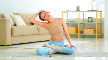 Young woman in sportswear doing yoga position in living room