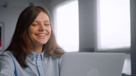Brunette medical university student connects to online lecturer and waves hand greeting teacher via gray laptop close viewの写真素材