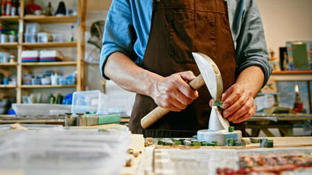 Young man with a hammer at work in studio close-upの写真素材