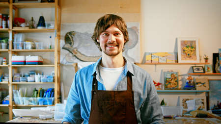 Smiling mature man in an apron looking at camera in studioの写真素材