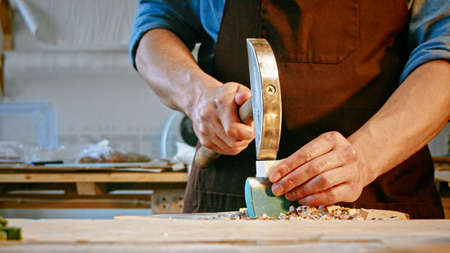 Young man with a hammer at work in studio close-upの写真素材