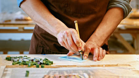 Male hands cutting a piece of glass in creative workshop close-upの写真素材