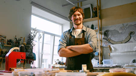 Young man in uniform looking at camera in workshopの写真素材