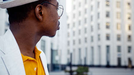 African American guy in glasses takes photo of local highrise office building on smartphone standing on city street close viewの写真素材