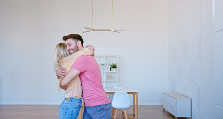 Romantic newlyweds with large brown cardboard boxes put things on floor pile in new apartment and give high five with joyful smilesの写真素材