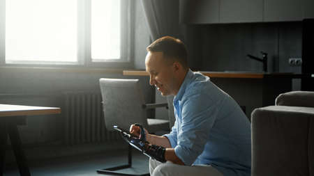 Concentrated disabled guy cyborg types and switches on smartphone at homeの写真素材
