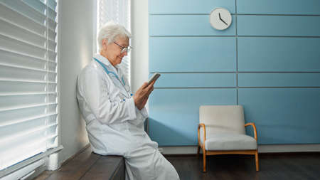 Skilled female doctor in white uniform consults patient at videocallの写真素材