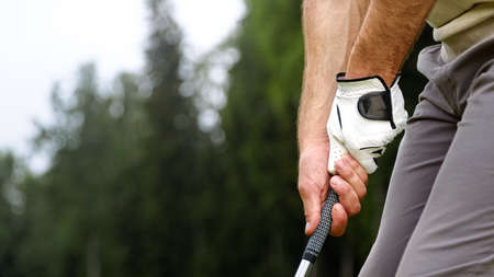 Hands of a playing man holding a golf club on the fieldの写真素材