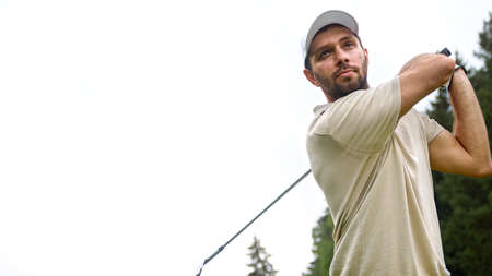 Young man in a cap playing golf on the field close-upの写真素材