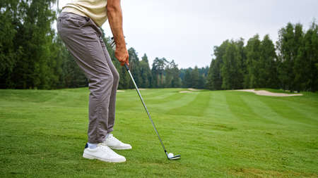 Young golfer in uniform making a hit with a club on the fieldの写真素材