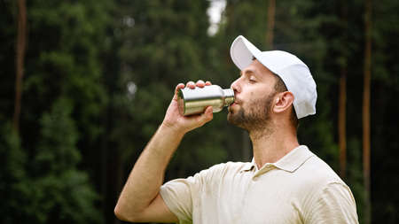 Young golfer drinking water from a bottle on a golf courseの写真素材