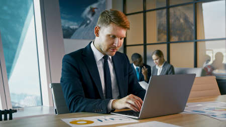Mature man in a suit typing on a laptop. Young businessman working in the officeの写真素材