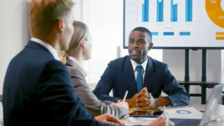 A young leader explaining to colleagues the profit analysis of the company. Business people working using technology in the officeの写真素材