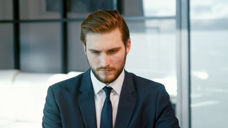 Serious man surfing the internet using a laptop. Young businessman with laptop in the officeの写真素材
