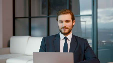 Serious man surfing the internet using a laptop. Young businessman with laptop in the officeの写真素材