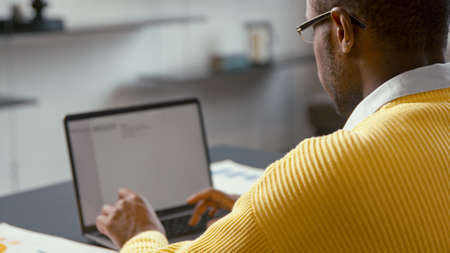 Young man typing on laptop from home office. Attractive man typing message from office at home