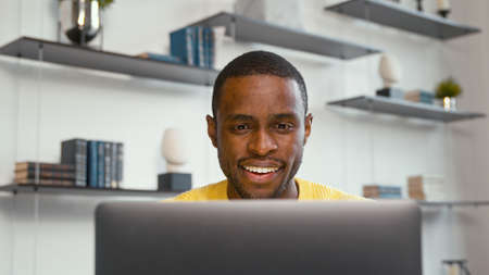 Smiling man working on laptop computer at home office. Male typing on laptop keyboard at office workplaceの写真素材