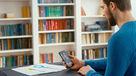 Young man communicating by videoconference at home office. Attractive man telling a projectの写真素材