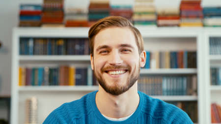 Smiling young teacher on the background of books in the officeの写真素材