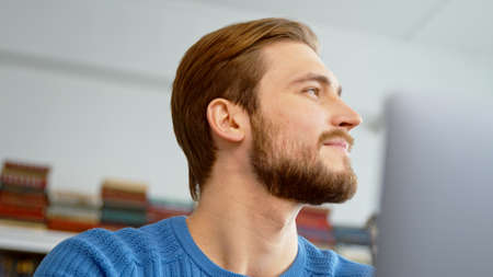 Young male surfing the internet using a laptop at home officeの写真素材