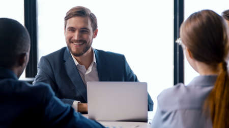 Two businessmen smiling while sitting at a table with a team. corporate people work concept