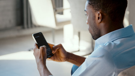 Young african american student taking notes using smartphone at home
