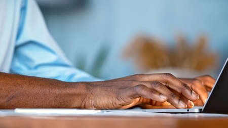 Hands of a young man typing on a laptop keyboard close-upの写真素材