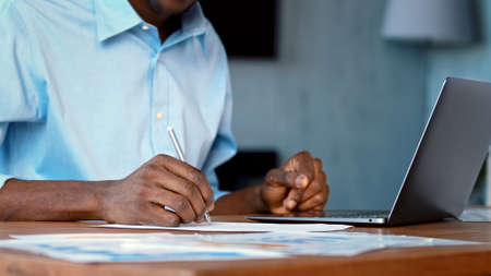 Young man writing with laptop in living room, close-upの写真素材