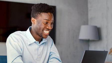 Smiling student writing typing on laptop keyboard in living roomの写真素材