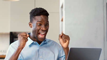 Successful young man who received good news on the internet rejoices at the victory in the officeの写真素材