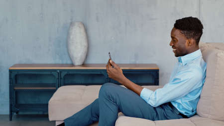 Young african american student having video conference using smartphone at homeの写真素材
