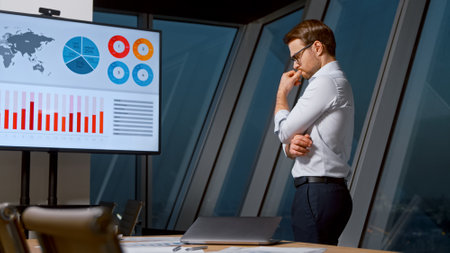 Thinking businessman looking at screen in meeting room in the eveningの写真素材