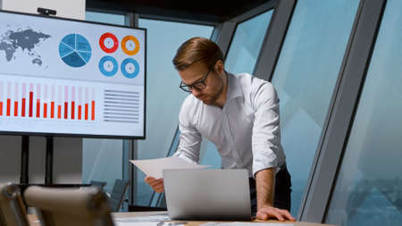 Young professional man working with laptop in meeting room at the windowの写真素材