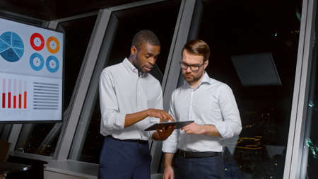 Businessmen using digital tablet together in front of office building windowsの写真素材